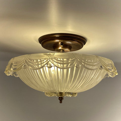 Vintage Art Deco style glass bowl ceiling light fixture with an antique brass canopy and warm illumination.