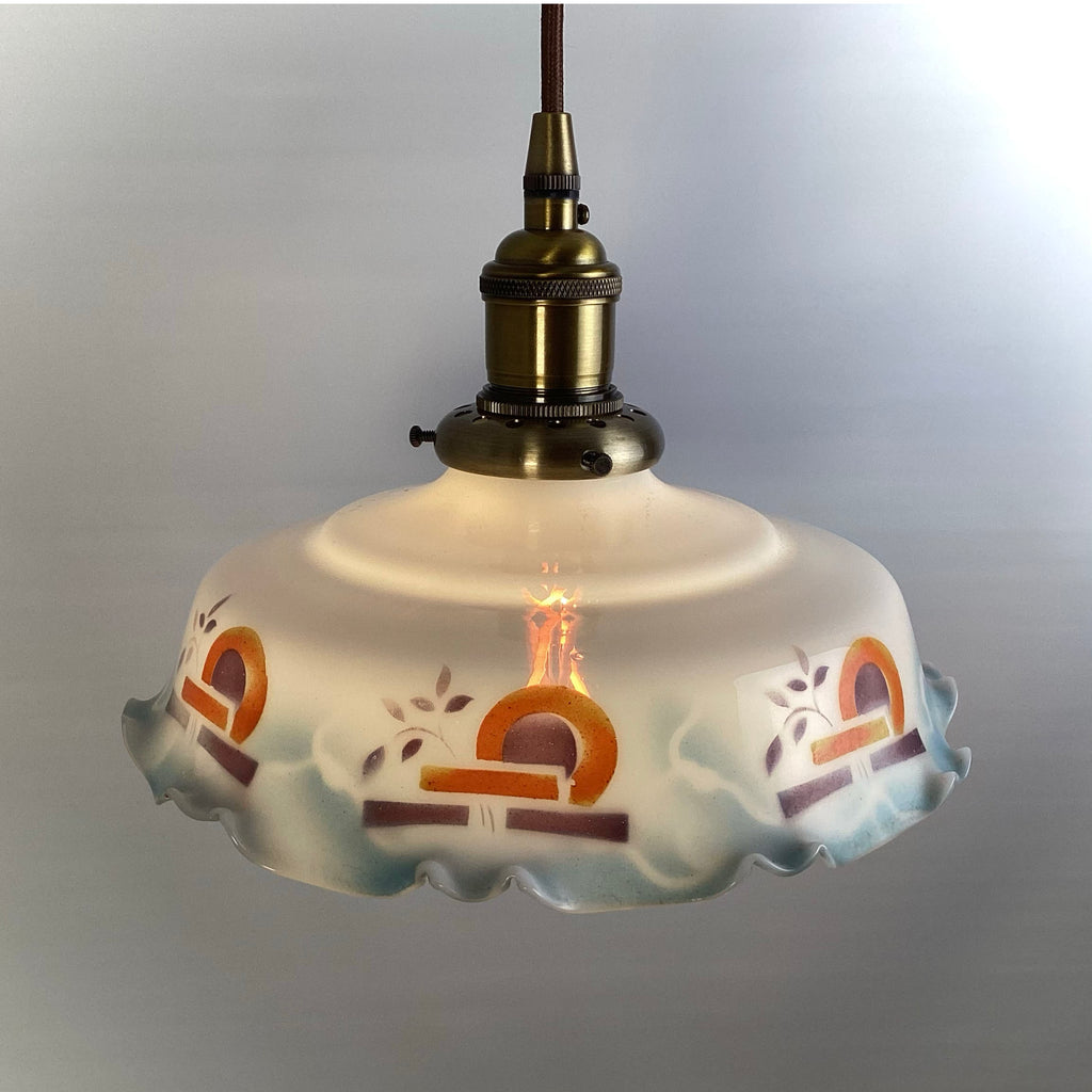A vintage Art Deco pendant light with a hand-painted scalloped glass shade illuminated against a neutral background.