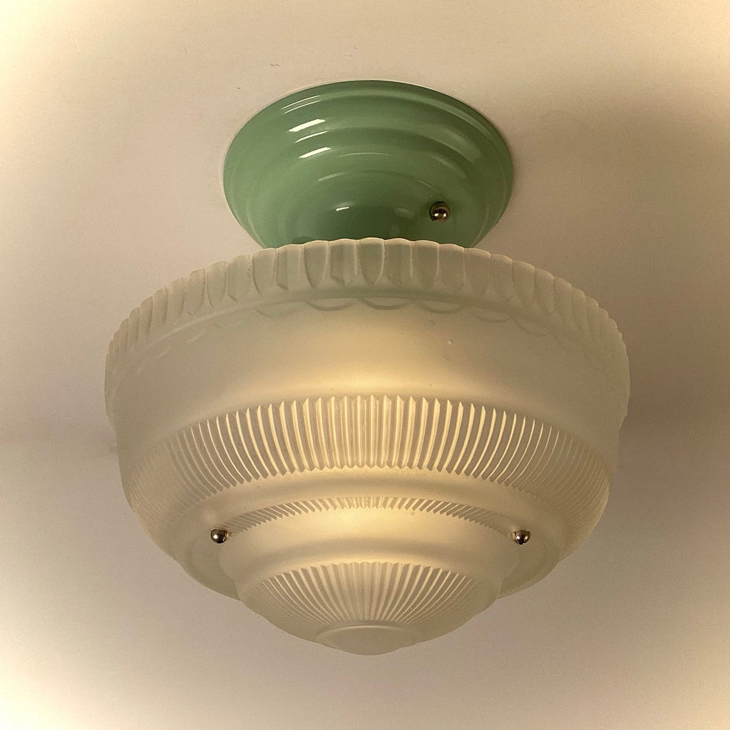 Vintage semi-flush ceiling light illuminated, featuring frosted ribbed glass shade and green metal canopy