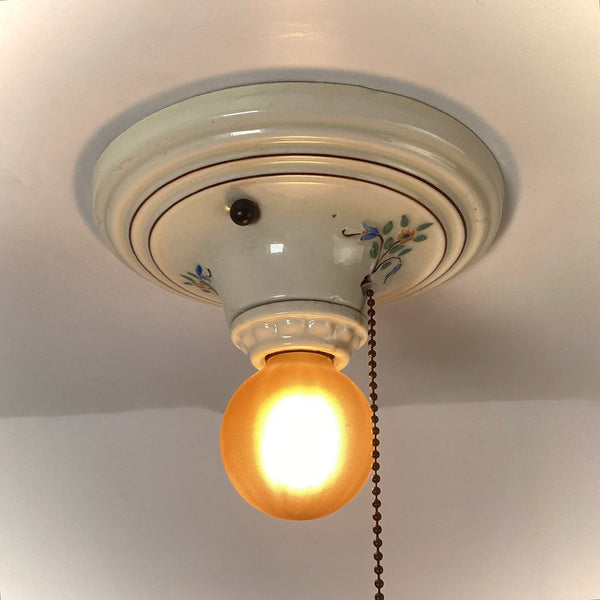 Vintage porcelain pull chain ceiling light with amber glass globe illuminated