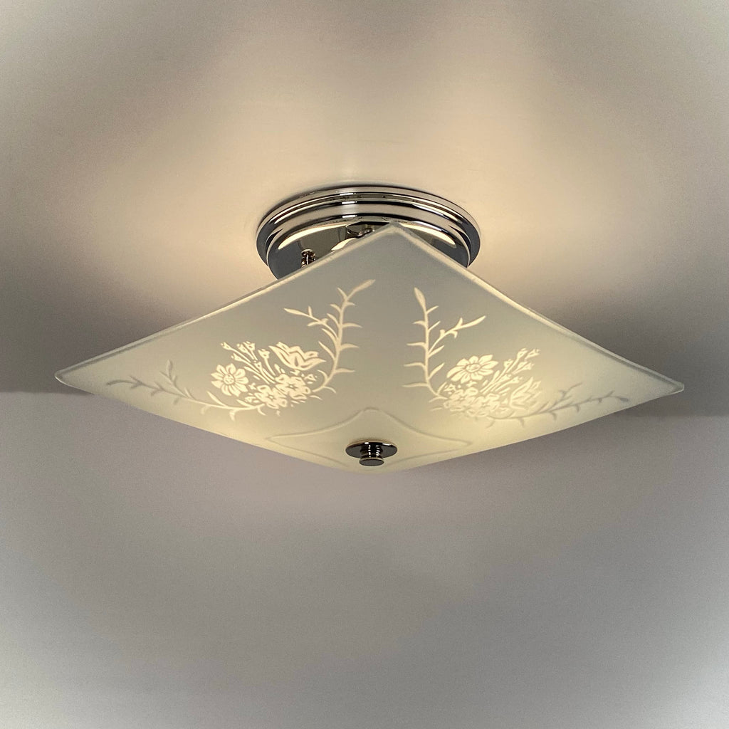 Vintage square frosted glass ceiling light illuminated, showing etched floral and botanical design