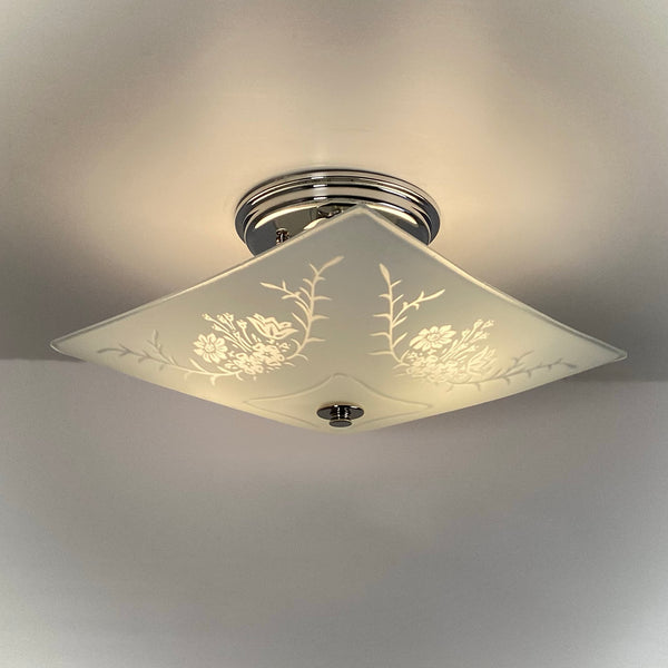Vintage square frosted glass ceiling light illuminated, showing etched floral and botanical design