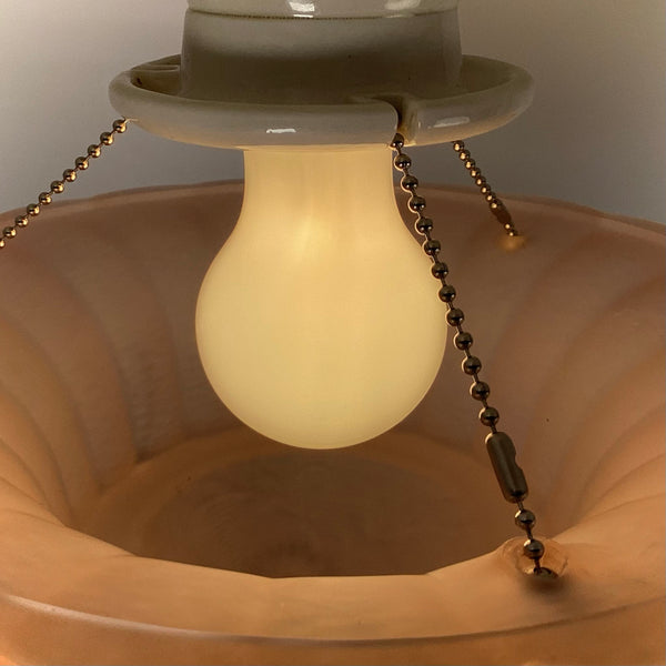Chain-supported peach glass shade and bulb detail on vintage Art Deco ceiling light