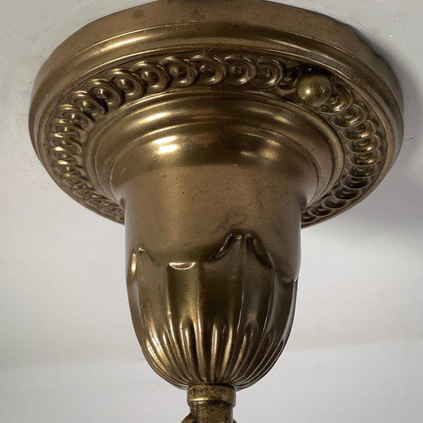 Close-up of the antique brass ceiling canopy on a 1920s pendant light, showing embossed beaded trim and fluted detailing.