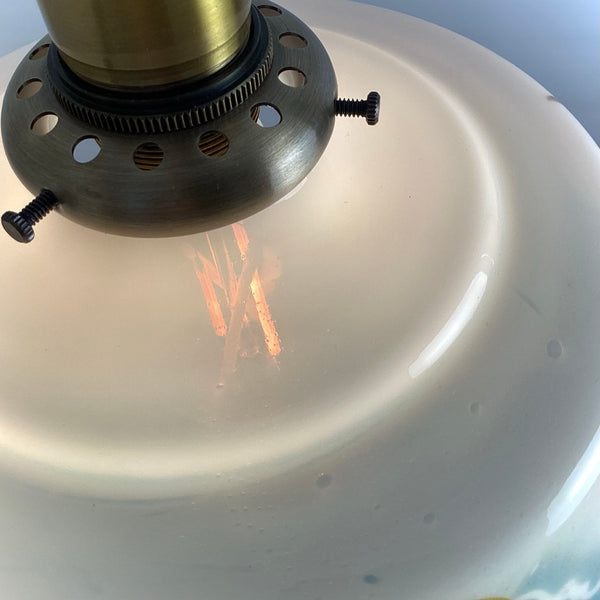 Top-down view of the brass hardware assembly and vented fitter for a hanging glass ceiling light.