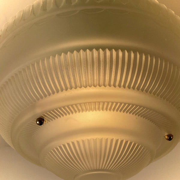 Close-up detail of illuminated ribbed frosted glass bowl on vintage semi-flush ceiling light