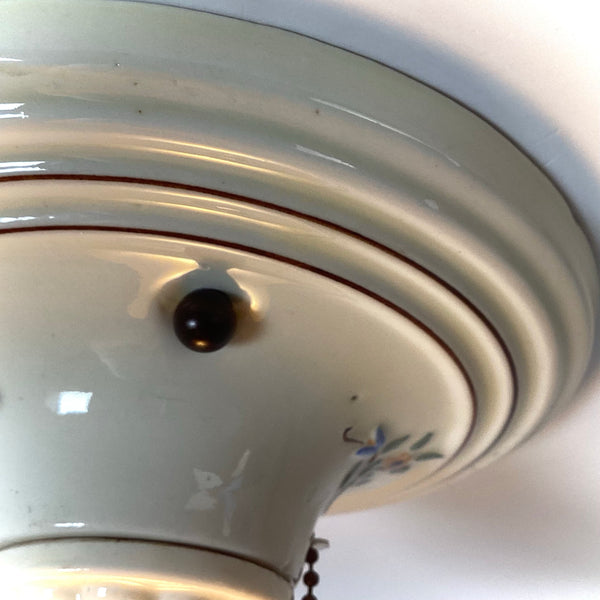 Close up of porcelain ceiling light showing floral detail and original patina