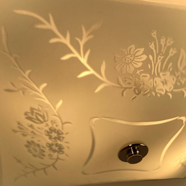 Detailed close-up of illuminated frosted glass ceiling light with etched floral motif