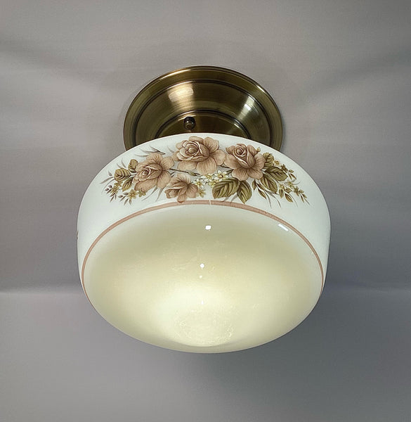 This semi-flush ceiling light features a vintage 1970s glass shade that combines hand-painted bands and a screen-printed floral motif. Screen printing is a technique widely used for applying designs and patterns onto various surfaces, including glass. In the 1970s, this method gained popularity due to its versatility and ability to produce high-quality, durable prints. Available at www.vintporium.com