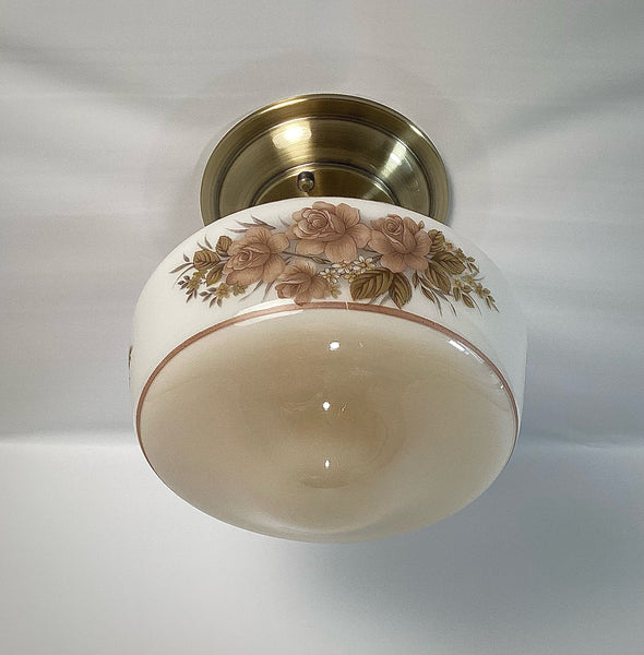 This semi-flush ceiling light features a vintage 1970s glass shade that combines hand-painted bands and a screen-printed floral motif. Screen printing is a technique widely used for applying designs and patterns onto various surfaces, including glass. In the 1970s, this method gained popularity due to its versatility and ability to produce high-quality, durable prints. Available at www.vintporium.com