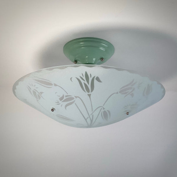 Mid-century modern ceiling light fixture with a pastel green canopy and frosted glass bowl featuring a tulip pattern, light off.