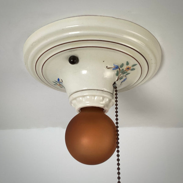 Vintage porcelain pull chain ceiling light with amber glass globe unlit
