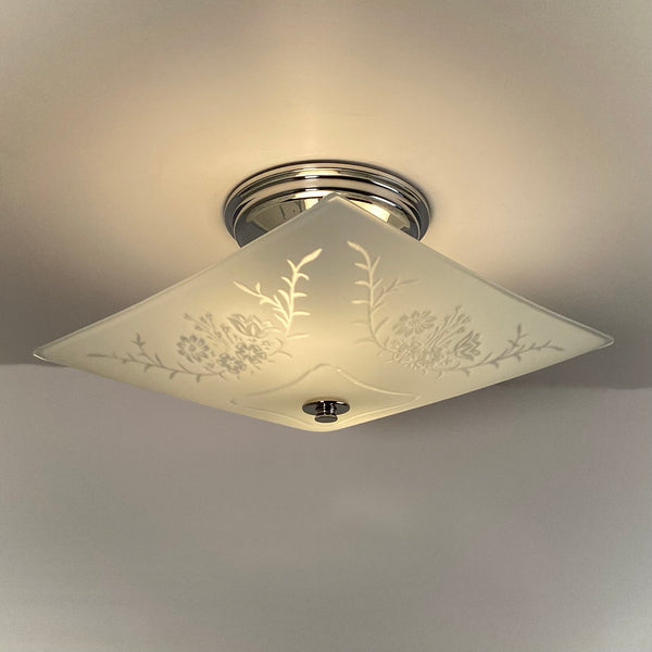 Mid-century square flush mount ceiling light lit, with soft glow through etched floral glass