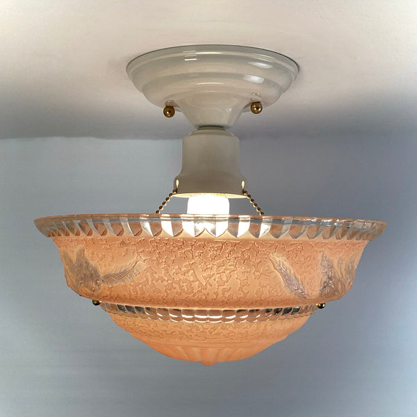 Side view of peach etched glass ceiling light showing pull chain socket and bulb