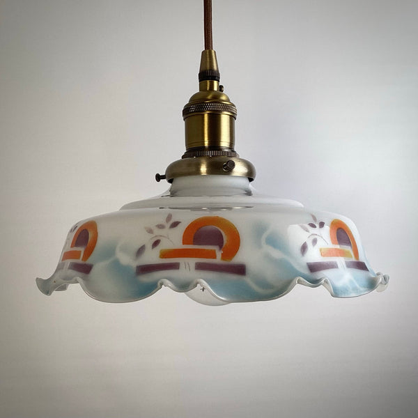 Close-up of a scalloped edge milk glass pendant shade with hand-painted arch designs.