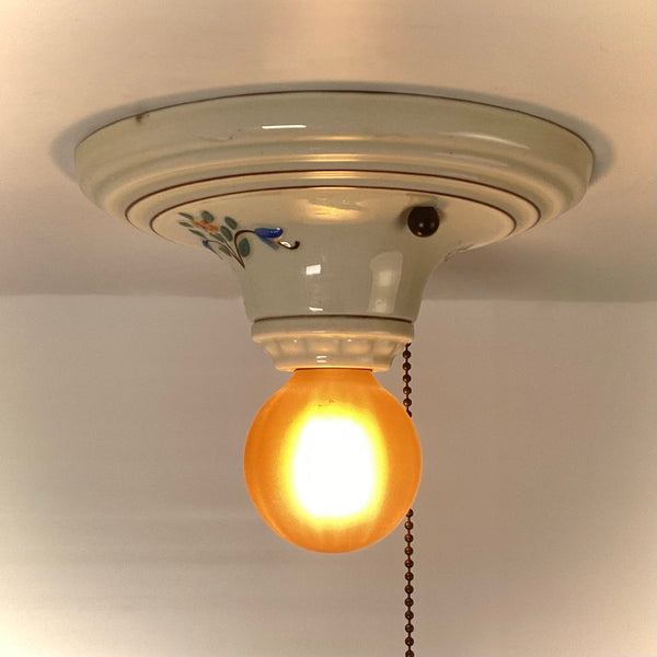 Front view of vintage porcelain ceiling fixture with amber glass globe