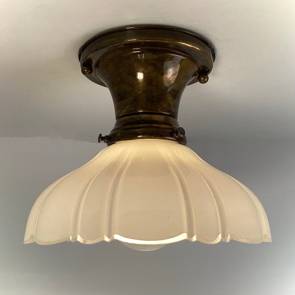 Brass flush mount ceiling light glowing through milk glass shade