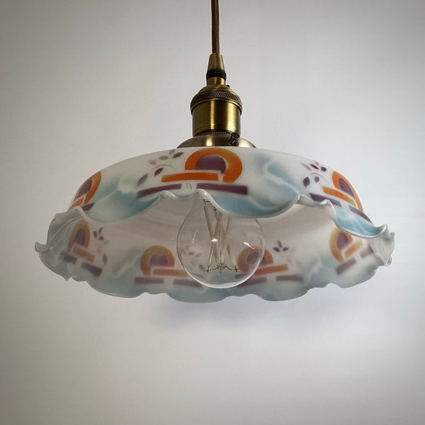 Vintage-inspired glass hanging lamp with a visible Edison-style filament bulb and aged brass hardware.