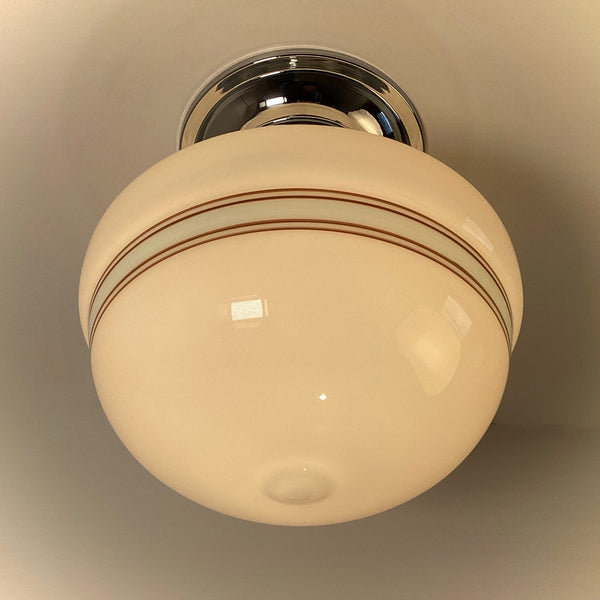 Round globe flush mount ceiling light with chrome base and horizontal striped glass shade, warm light.