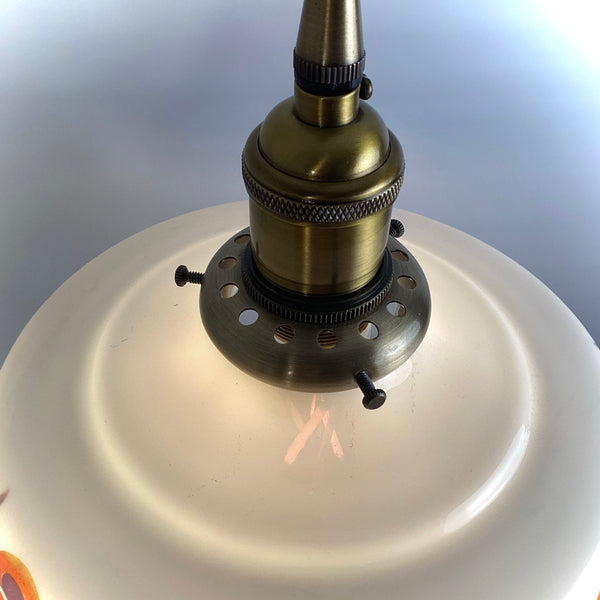 An aged brass lamp socket and shade fitter with adjustable thumb screws for a vintage pendant light.