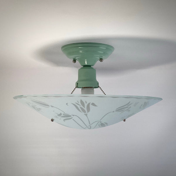 Close-up of the vintage mint green mounting hardware and socket of a floral glass ceiling light.