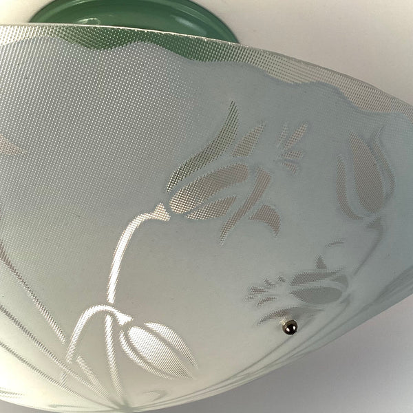 Macro shot of the textured frosted glass on a vintage light fixture, highlighting the embossed tulip petal details.