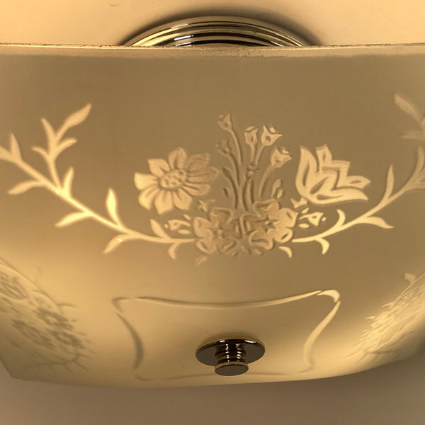 Close-up detail of etched floral design on frosted glass ceiling light when illuminated