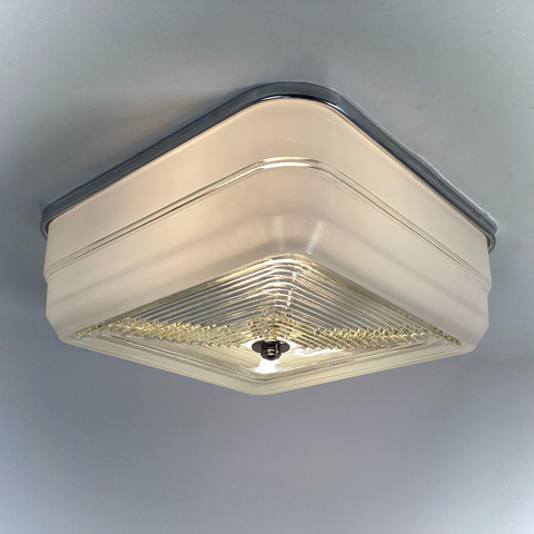 Vintage mid-century square flush mount ceiling light with aluminum fixture base and stepped glass diffuser, illuminated view — Vintporium