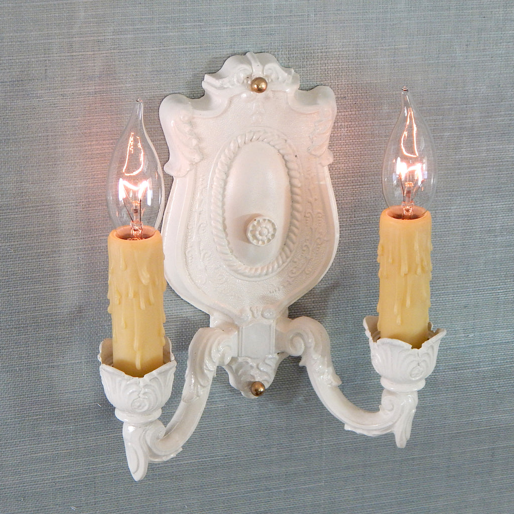 The shabby chic style is characterized by its old-fashioned charm and unique distressed details. This delightfully handsome antique Art Kast sconce embraces its shabby chic look with a blend of canvass white paint, over a pot petal cast body, and honey-colored poly wax candelabra covers. The fixture has been renovated with new sockets, wires, mounting hardware, etc. making it convenient to install. Available at www.vintporium.com